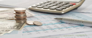 Dollar bills and coins on documents with a calculator Fee Calculation